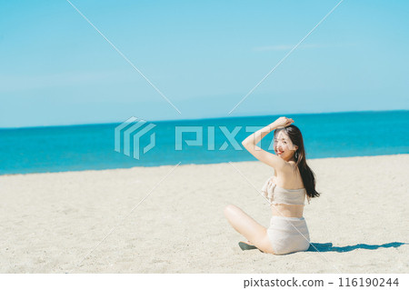 穿著泳衣的年輕女子坐在沙灘上 116190244