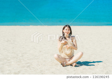 穿著泳衣的年輕女子坐在沙灘上 116190245