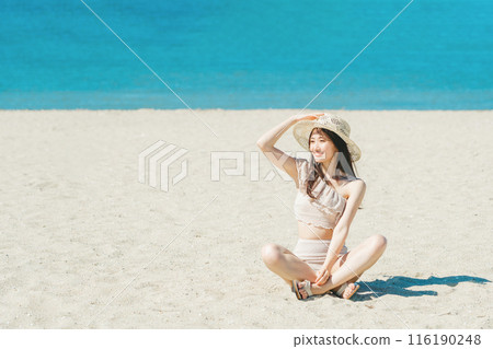 穿著泳衣的年輕女子坐在沙灘上 116190248