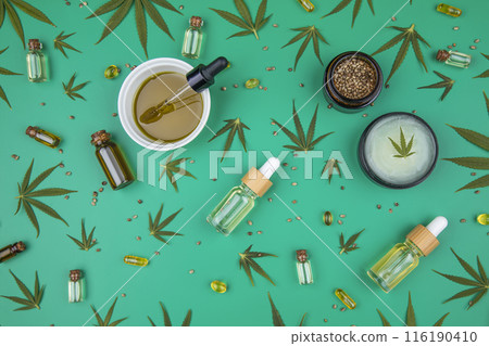 Flat lay composition with hemp oil and hemp leaves on green color background 116190410