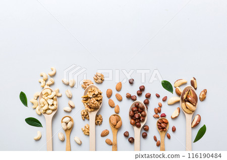 mixed nuts in white wooden spoon. Mix of various nuts on colored background. pistachios, cashews, walnuts, hazelnuts, peanuts and brazil nuts 116190484