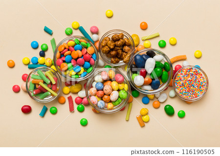 different colored round candy in bowl and jars. Top view of large variety sweets and candies with copy space 116190505