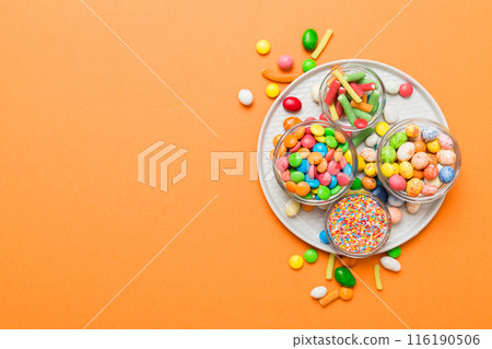 Multicolored candies in a bowl on a colored background. birthday and holiday concept. Top view with copy space 116190506