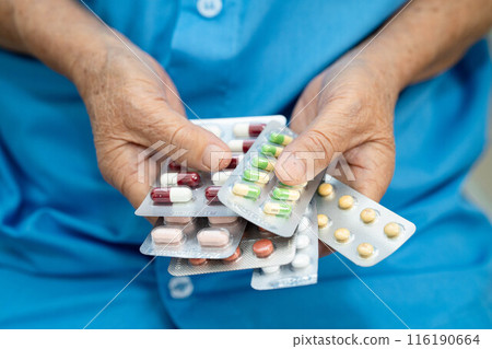 Senior Asian woman holding capsule pills drug in blister packaging for treatment infection patient in hospital. Senior Asian woman holding capsule pills drug in blister packaging for treatment infection patient in hospital. 116190664