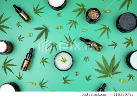 Flat lay composition with hemp oil and hemp leaves on green color background 116190782