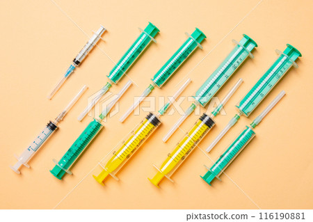 Top view of medical syringes with needles at orange background with copy space. Injection treatment concept Top view of medical syringes with needles at orange background with copy space. Injection treatment concept 116190881