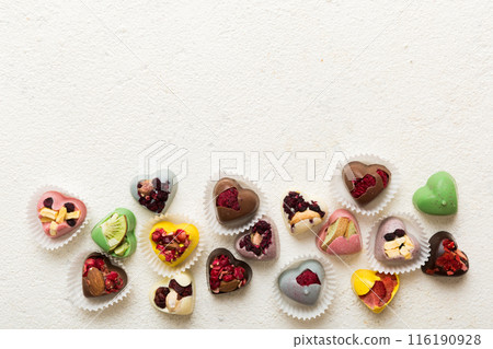 chocolate sweets in the form of a heart with fruits and nuts on a colored background. top view with space for text, holiday concept 116190928
