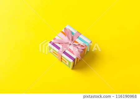 wrapped Christmas or other holiday handmade gift box in color paper with ribbon on colored background. Present box, decoration of gift on colored table, top view with copy space 116190968