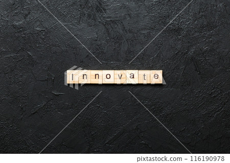 INNOVATE word written on wood block. INNOVATE text on cement table for your desing, concept 116190978