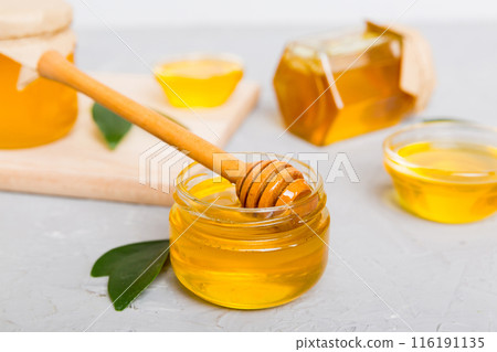 Honey in jar with leaves and honey dipper on colored background top view with copy text Honey in jar with leaves and honey dipper on colored background top view with copy text 116191135