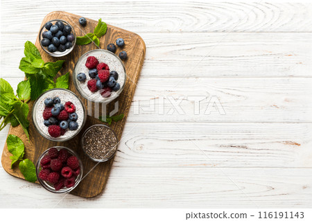 Healthy breakfast or morning with chia seeds vanilla pudding raspberry and blueberry berries on table background, vegetarian food, diet and health concept. Chia pudding with raspberry and blueberry 116191143