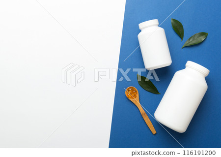 Omega-3 capsules lie in white bottle on a table with green leaves background. Fish oil tablets. Biologically active additives. omega 6, omega 9, vitamin A, E, D, vitamin D3 top view with copy space 116191200