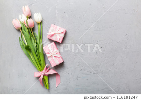 Pink tulips flowers and gift or present box on colored table background. Mothers Day, Birthday, Womens Day, celebration concept. Space for text top view 116191247