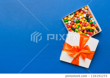 Set of different sweet candy in a paper box with a satin ribbon on a colored background. Holiday concept Set of different sweet candy in a paper box with a satin ribbon on a colored background. Holiday concept 116191255