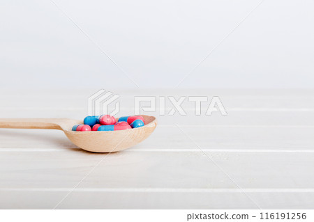 Vitamin capsules in a spoon on a colored background. Pills served as a healthy meal. Red soft gel vitamin supplement capsules on spoon Vitamin capsules in a spoon on a colored background. Pills served as a healthy meal. Red soft gel vitamin supplement capsules on spoon 116191256