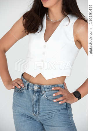 Happy beautiful girl posing in a new hot summer look. Wearing blue jeans and white waistcoat 116191435