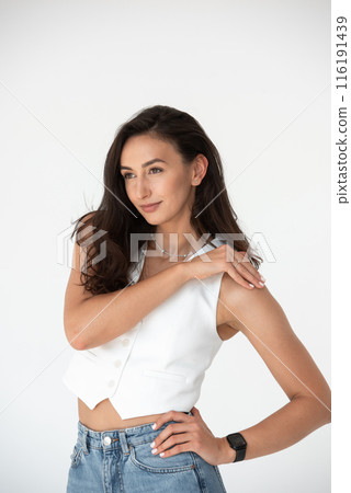 Happy beautiful girl posing in a new hot summer look. Wearing blue jeans and white waistcoat 116191439