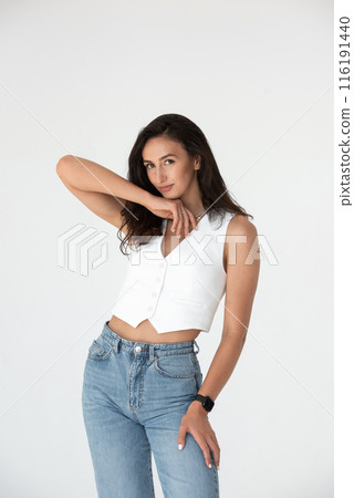 Happy beautiful girl posing in a new hot summer look. Wearing blue jeans and white waistcoat 116191440