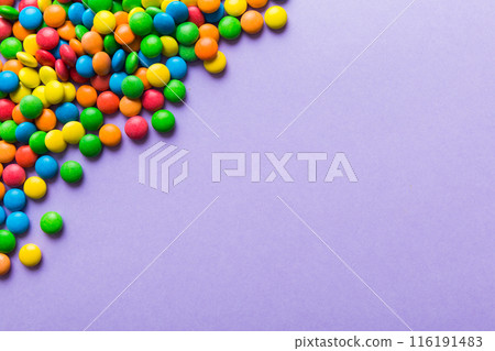Mixed collection of colorful candy, on colored background. Flat lay, top view. frame of colorful chocolate coated candy 116191483