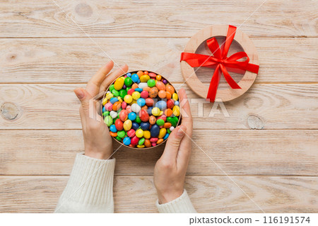 Female hands with delicious candies in box on color background Female hands with delicious candies in box on color background 116191574