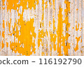 Close up of a weathered corrugated metal surface with peeling yellow paint, revealing rust and wear underneath. 116192790