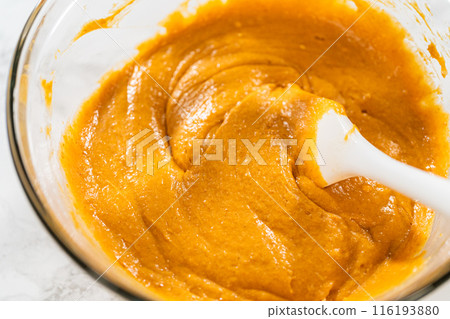 A close-up view of expertly blended ingredients in a large mixing bowl for a mouthwatering homemade pumpkin bundt cake. 116193880