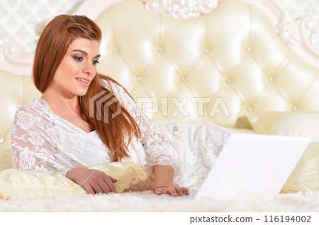 Portrait of young beautiful woman with coffee cup on bed Portrait of young beautiful woman with coffee cup on bed 116194002