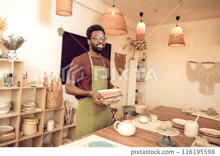 Dark-skinned man in eyeglasses working with pottery in his workshop 116195598
