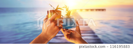 Male and female hands clinking glasses with cocktails, celebrating vacation against beautiful ocean background during sunset 116195883