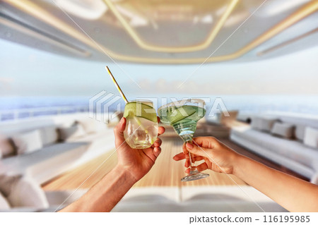 Tropical luxury travels. Focus on male and female hands holding refreshing cocktails with cucumber slices. Enjoying drinks on luxurious yacht 116195985