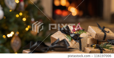 Christmas gifts with black bows on background of burning fireplace and christmas tree 116197006