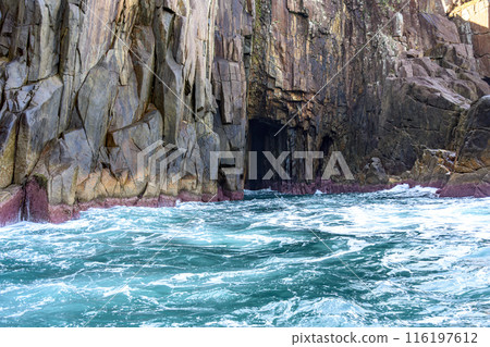 Cave in the cliff over the sea 116197612