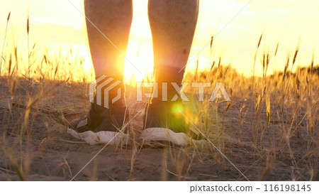 close-up of an athletes legs walking uphill. slow steps of mens legs against the background of a beautiful sunset. leg health and sports close-up of an athletes legs walking uphill. slow steps of mens legs against the background of a beautiful sunset. leg health and sports 116198145