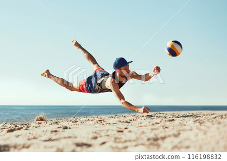 Focused man in sportswear playing beach volleyball by the sea, hitting all in jumbo and falling down in sand. Focused man in sportswear playing beach volleyball by the sea, hitting all in jumbo and falling down in sand. 116198832