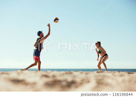 Focused man serving ball to concentrated young woman, friends playing beach volleyball on beach by the sea under sun sea sky. Low angle view 116198844