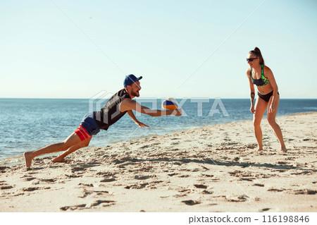 Dynamic beach volleyball game, with male and female players in motion, playing dynamic game on sunny beach Dynamic beach volleyball game, with male and female players in motion, playing dynamic game on sunny beach 116198846