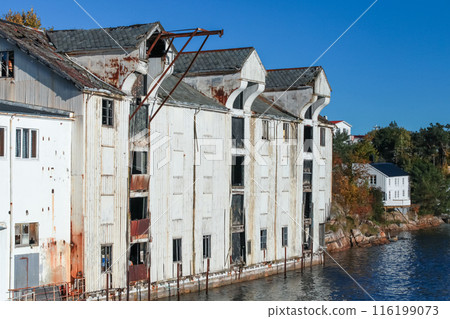 Coastal Norwegian with abandoned white wooden port barn 116199073