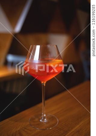 A refreshing orange cocktail in a wine glass on a wooden table, perfect for a relaxing evening 116199285