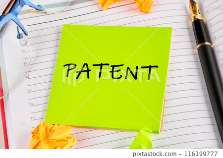 PATENT word written on a light green sticker lying on the notebook PATENT word written on a light green sticker lying on the notebook 116199777