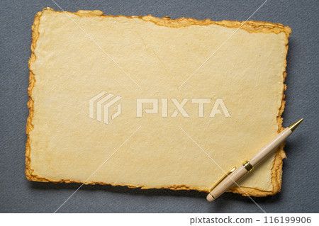 stack of tan toned heavyweight deckle edge paper sheets with a stylish pen 116199906
