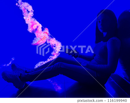 A girl in an aquarium against the background of floating jellyfish in a colourful aquarium 116199940