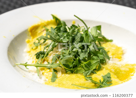 Ravioli, stuffed pasta filled with cheese, arugula topped, grated cheese, served in a lemon zest sauce 116200377