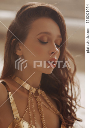 A woman with long brown hair wearing gold chains. A woman with long brown hair wearing gold chains. 116201034