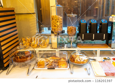 Italian hotel breakfast buffet, pastries, croissants, cookies, cereal dispensers, cold cuts, cheese slices Italian hotel breakfast buffet, pastries, croissants, cookies, cereal dispensers, cold cuts, cheese slices 116201397
