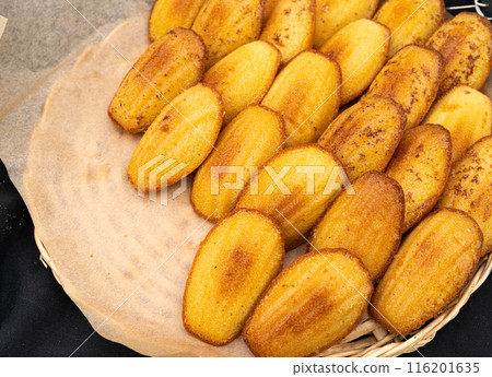 Madeleines or French tea cakes in a basket, spongy texture cookies, golden soft biscuits, tea snacks Madeleines or French tea cakes in a basket, spongy texture cookies, golden soft biscuits, tea snacks 116201635