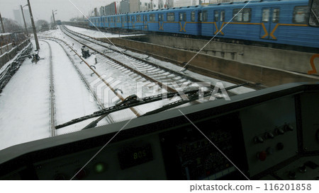 A subway train travels on rails through a snowy city. Winter in a big city. 116201858
