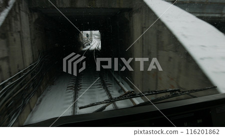 The subway train goes into the tunnel at the green light of the traffic light. 116201862