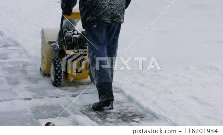 Man removes snow with the help of snow removal equipment. Snow removal winter season. 116201934