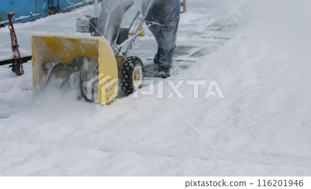 Janitor cleans snow with tractor. Snow removal. Cleaning the streets from snow. Snowblower. 116201946