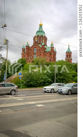 Uspensky Cathedral in Helsinki - red brick church with green blue roof on a cloudy day view from the road with traffic 116201952
